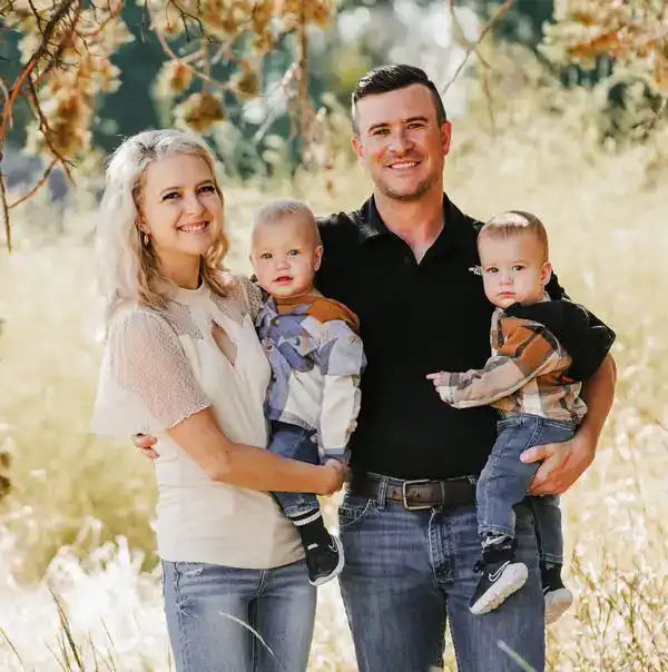 Dr. McCormick standing next to his wife with bright smiles, each holding their young sons .Cascade View Family Dental